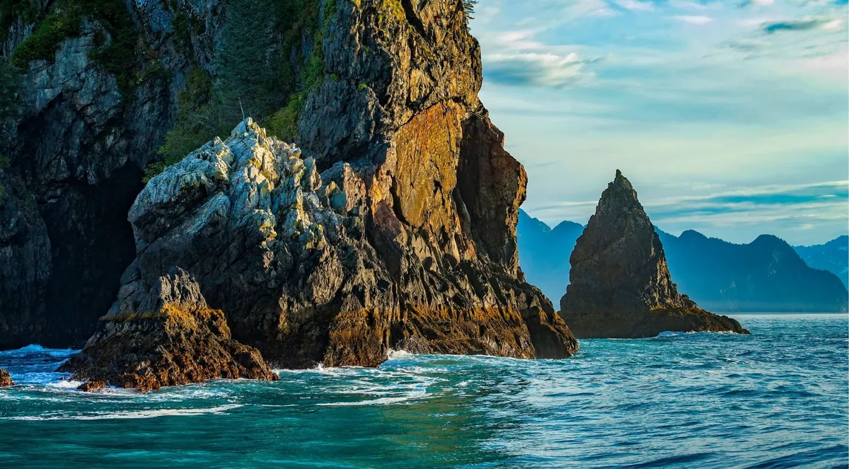 Sea cliffs and a rock spire lit by golden autumn light