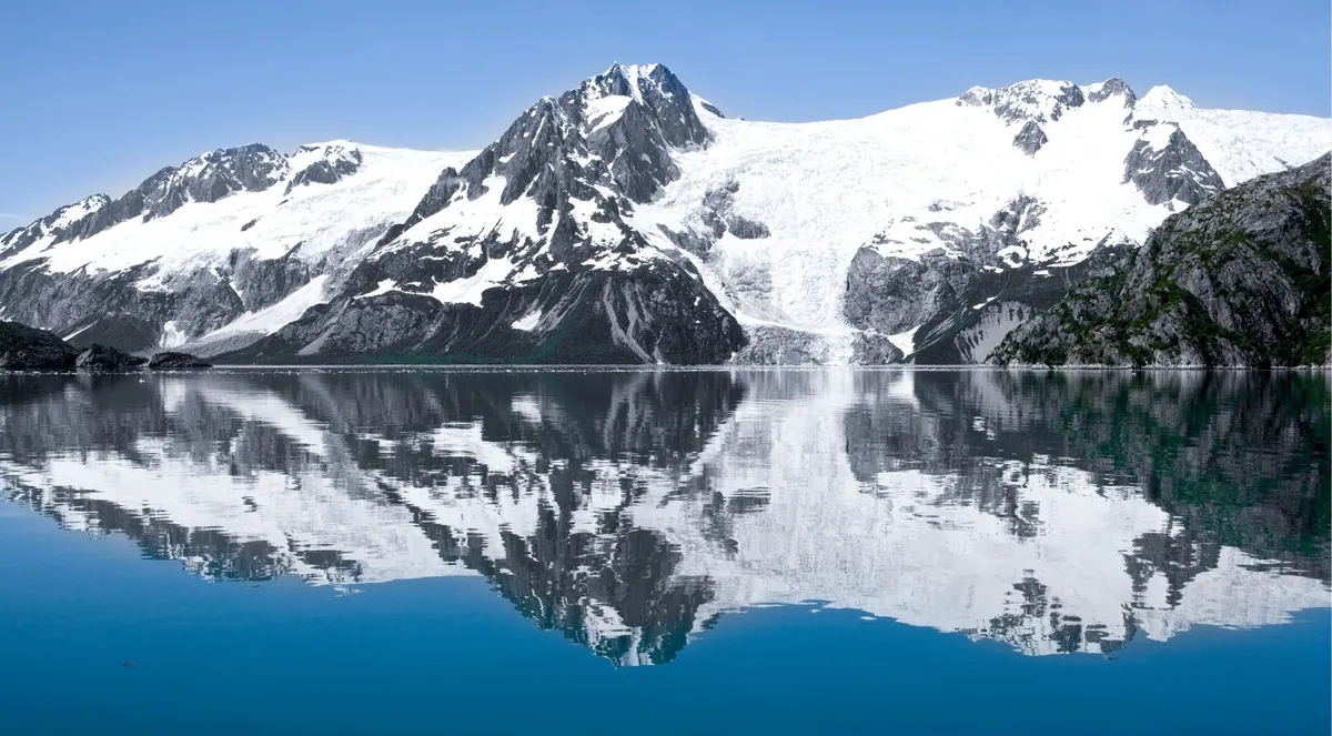 Snow-covered Kenai mountains reflected in still winter water